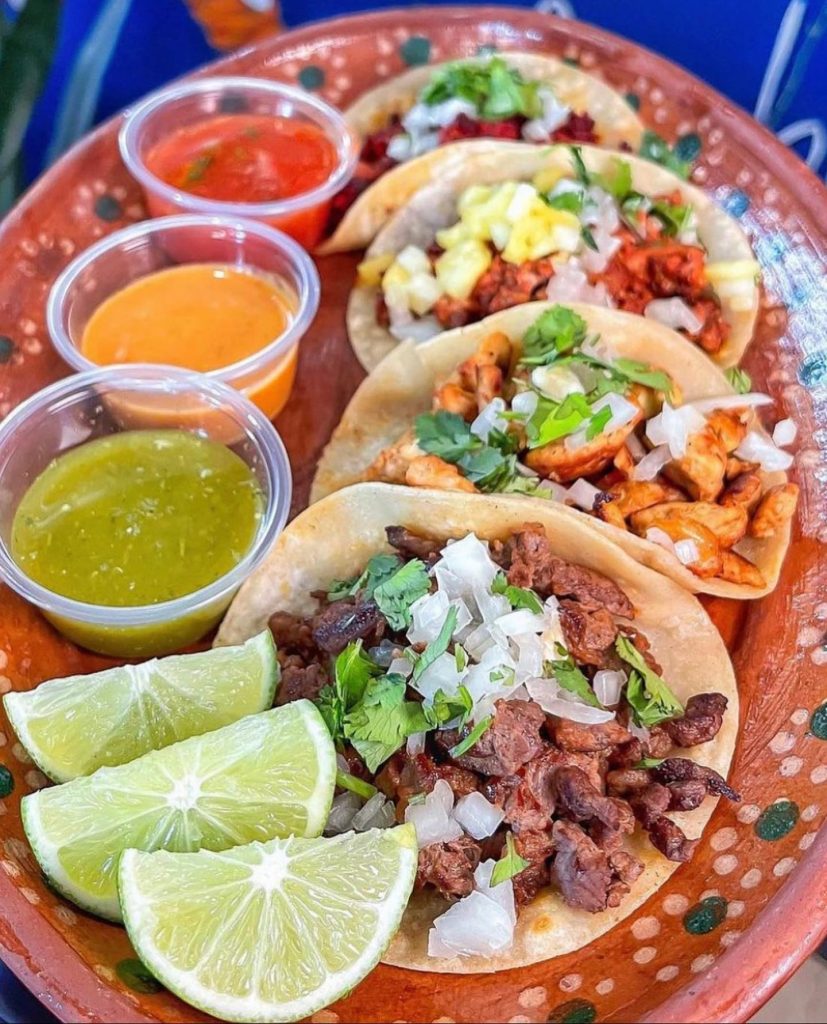 A colorful plate of tacos with different salsas