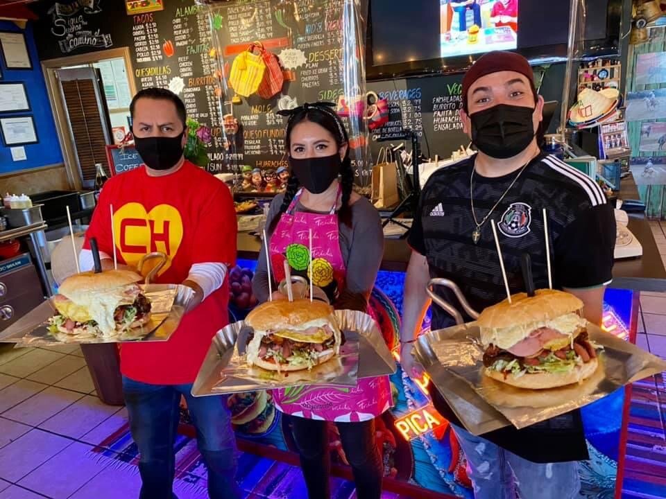 The La Vecindad team holding three Super Tortas inside the restaurant